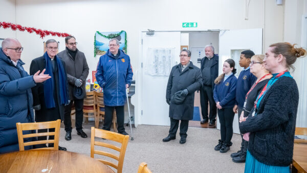 Group of people standing around the edges of a room at the Caritas Lalley Centre in Collyhurst 