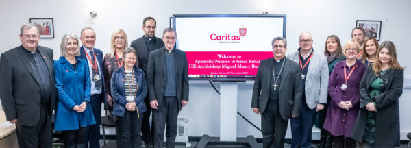 Group of people standing with Nuncio in front of a screen that says welcome to him.