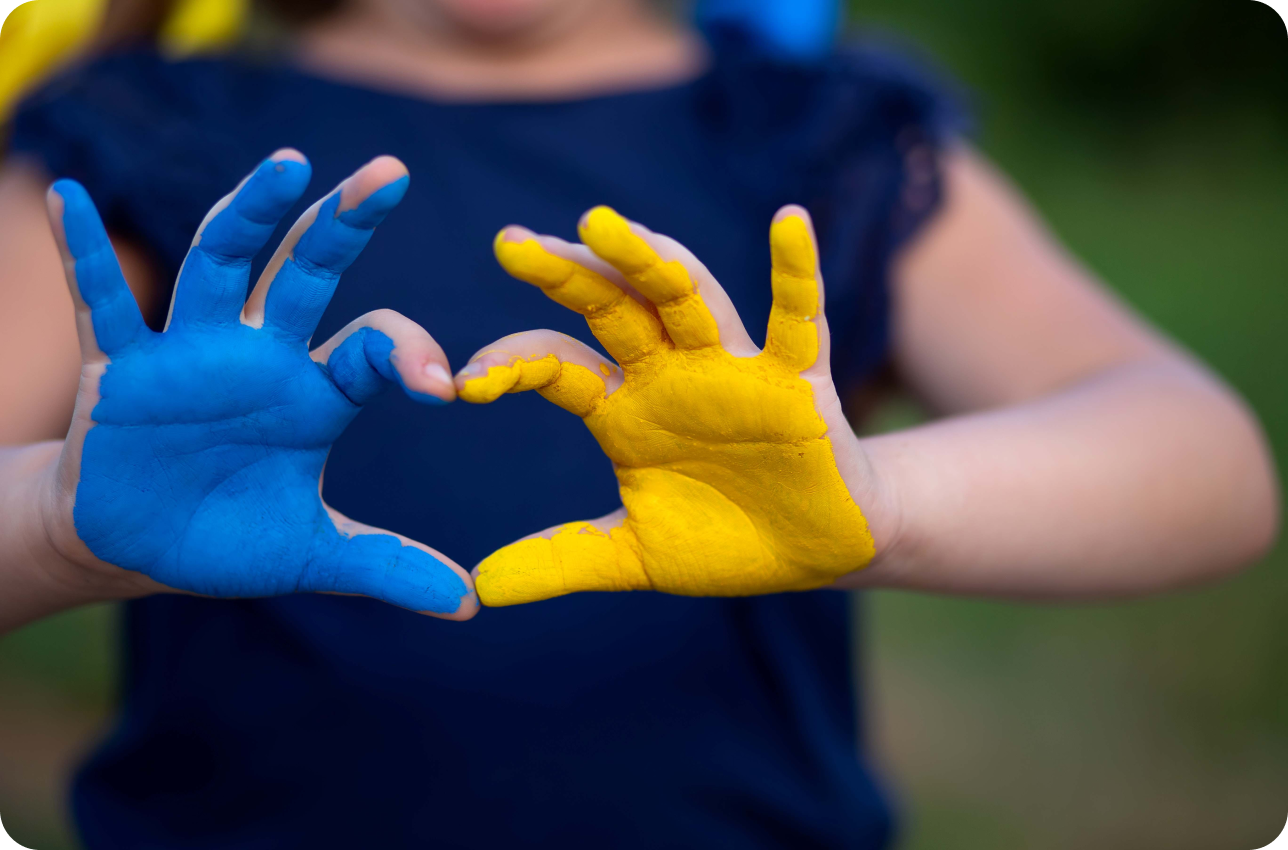 hands making heart shape one painted blue and one painted yellow