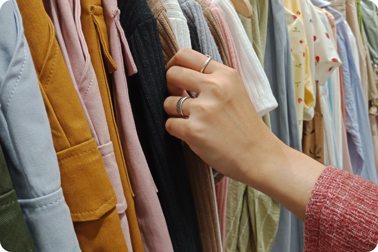Hand touching a rack of jumpers and cardigans