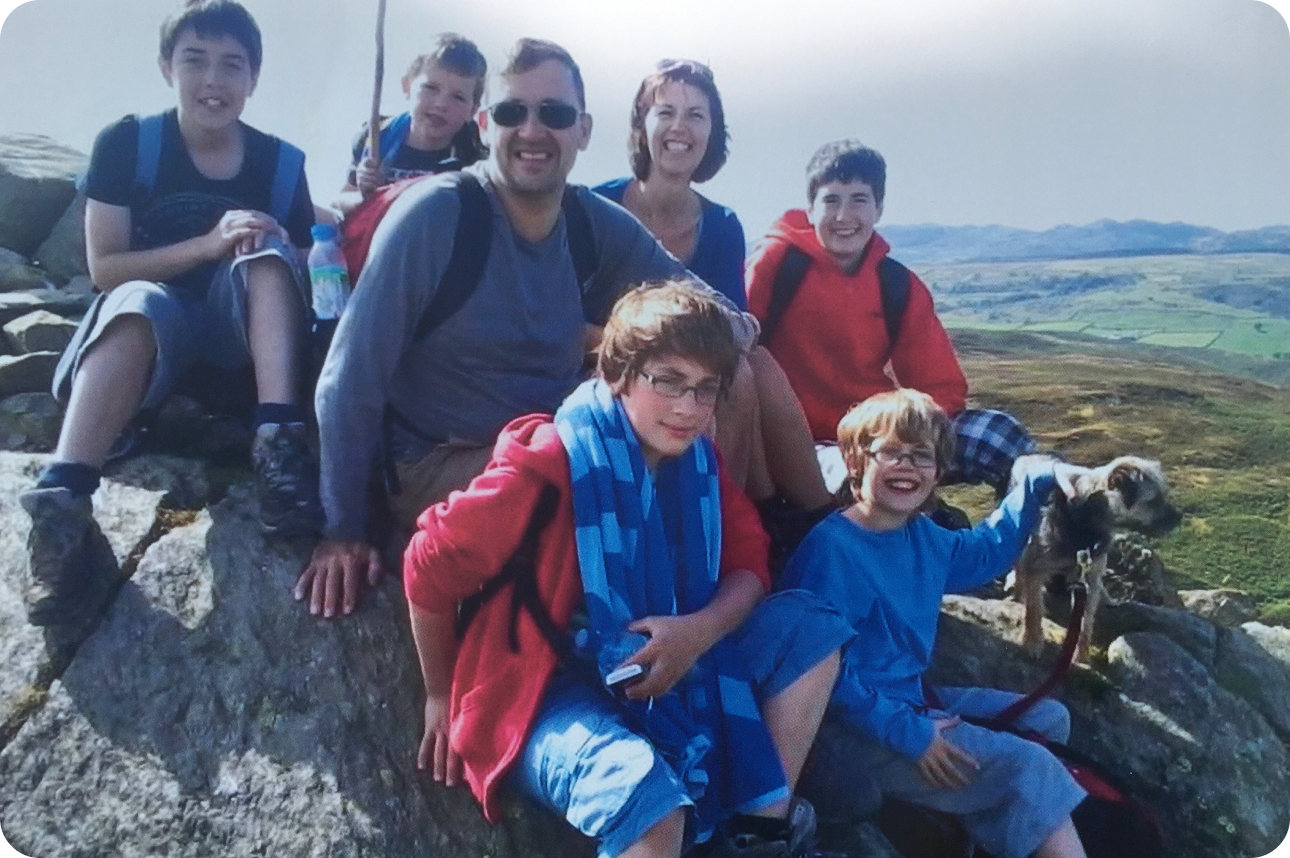 Michael sitting on a rock with his wife and children