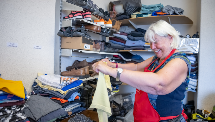 Lady in red apron sorting clothing on shelves