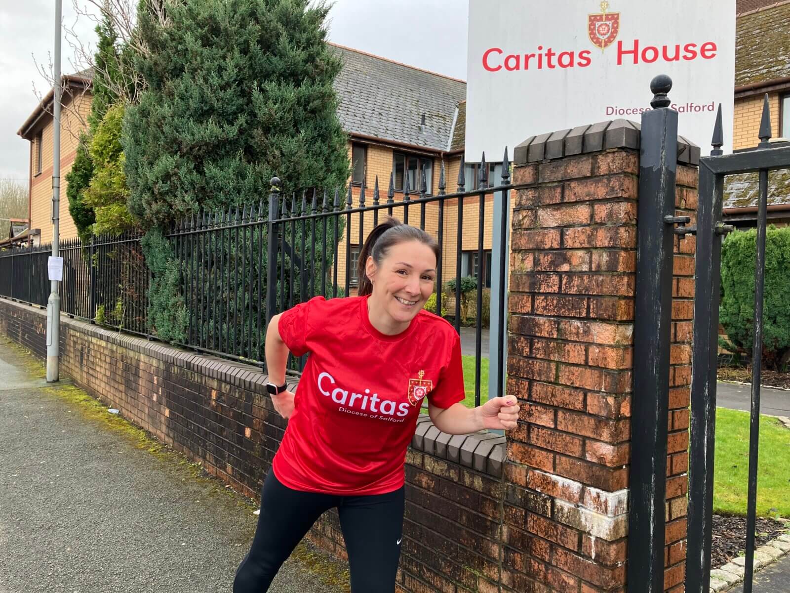 Person in red Caritas branded tshirt running in front of Caritas House building