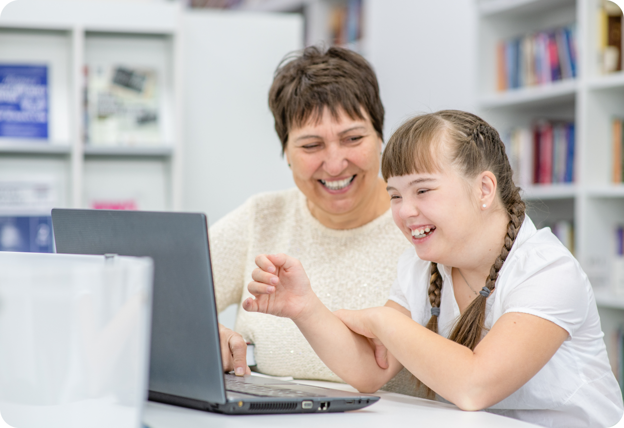 Woman and girl laughing while looking at laptop